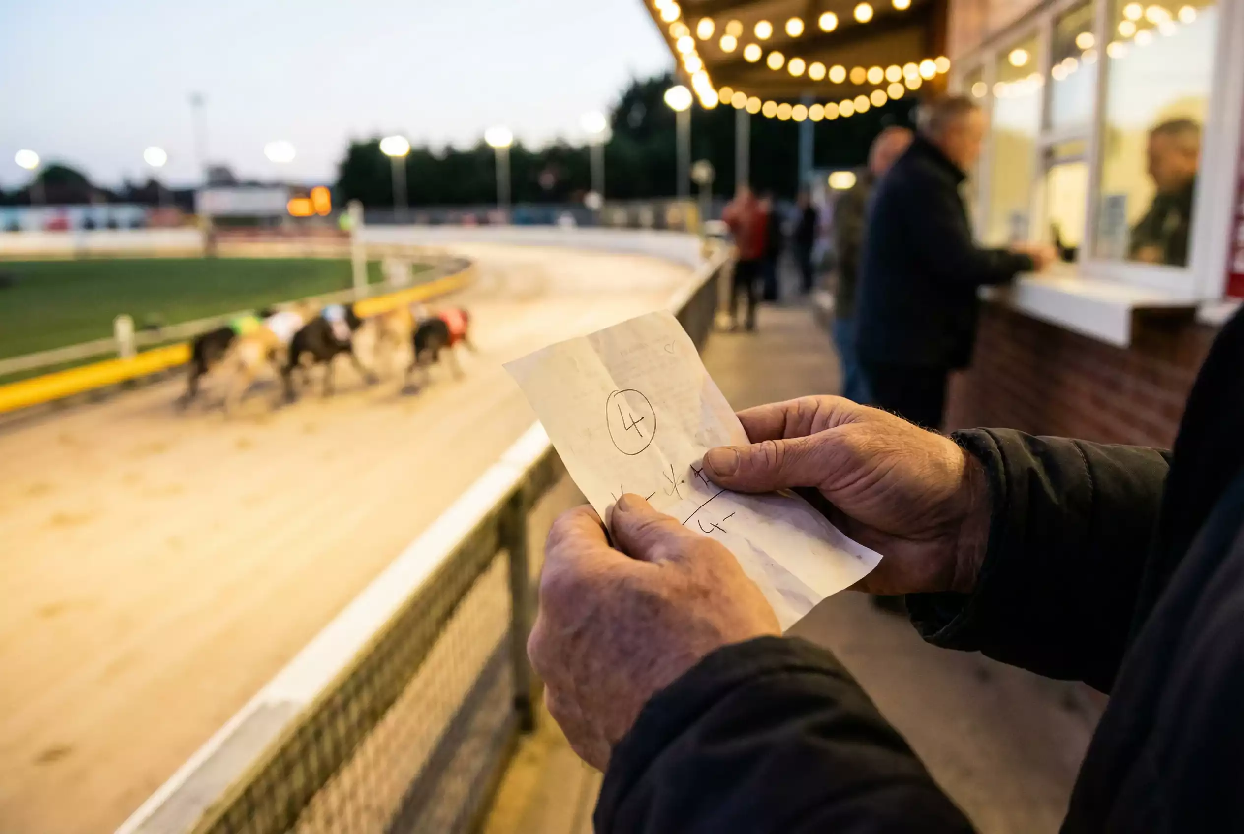 Punter holding betting slip with trap number selection at greyhound stadium