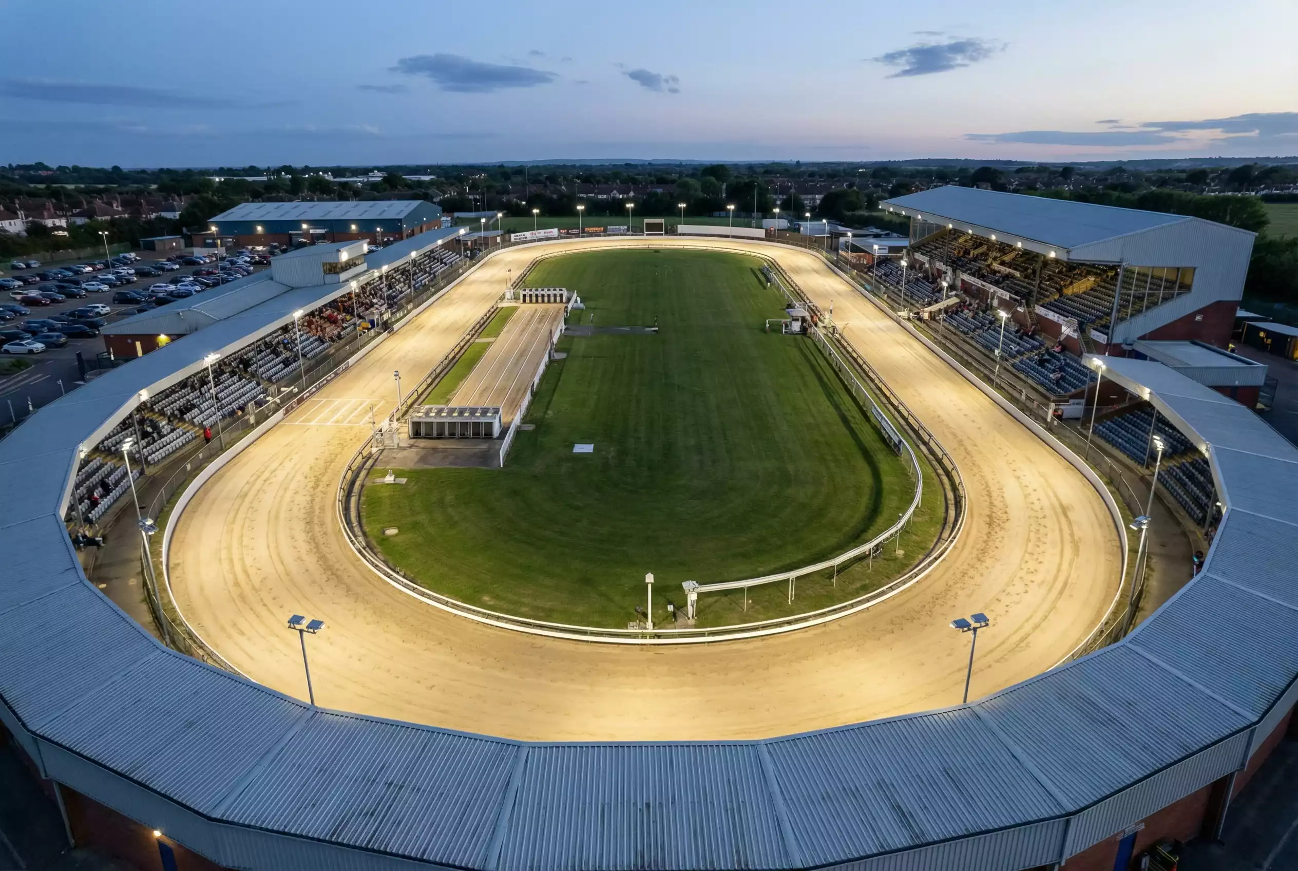 Aerial view of a British greyhound racing stadium showing the oval track and starting position